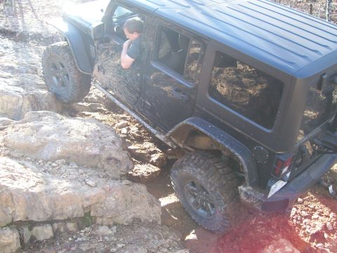 2007 Jeep Wrangler - A black 2007 Jeep Wrangler is shown off-roading over large rocks and mud.