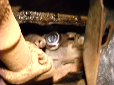 1993 Ford C-150 (Centurion Conversions) - A freeze plug is visible on the engine block, surrounded by oily residue and engine components.