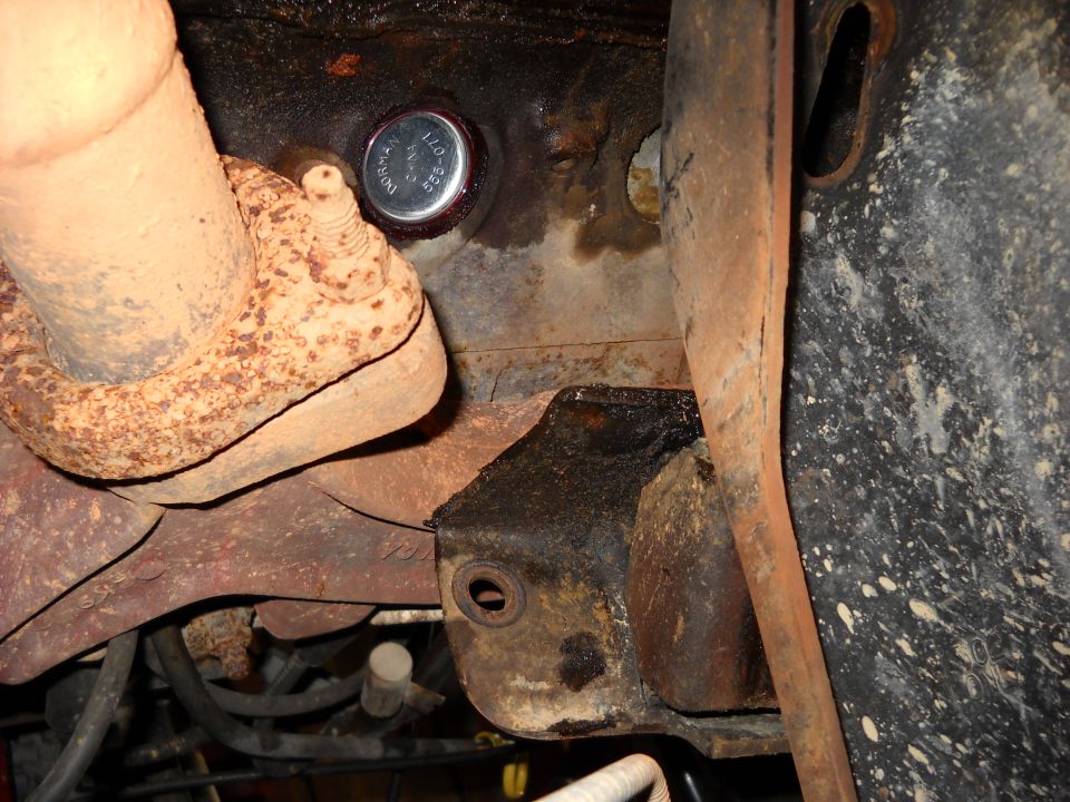 Close-up of a freeze plug on an engine block, next to exhaust pipe. Text on plug reads 'Dorman 550-071'