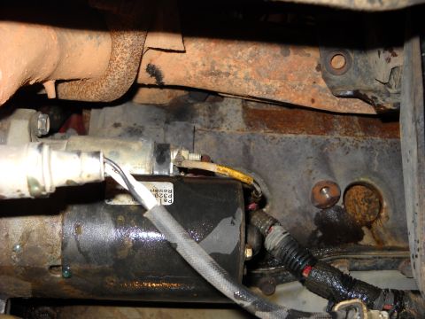 1993 Ford C-150 (Centurion Conversions) - Close-up view of a starter motor assembly, showing wiring and engine block components.