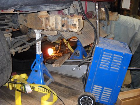1993 Ford C-150 (Centurion Conversions) - Working on the frame of a vehicle with welding equipment and jack stands.