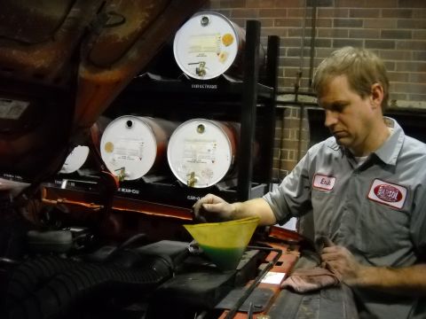 1993 Ford C-150 (Centurion Conversions) - Mechanic Erik performing maintenance, pouring fluid into the engine bay.
