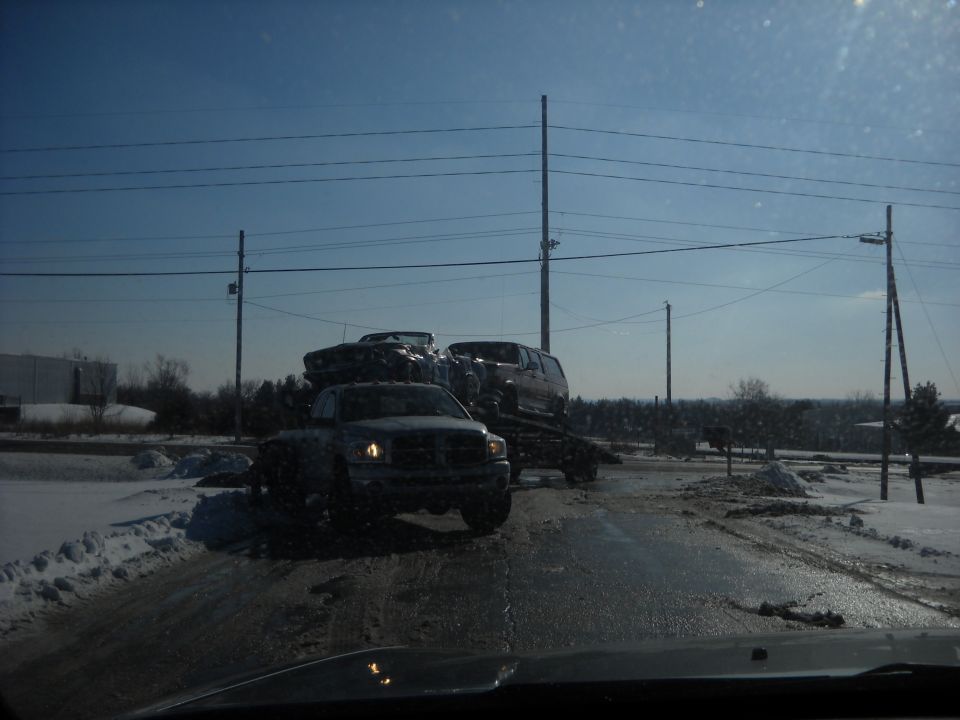 Truck towing a car and an SUV on a trailer in the snow