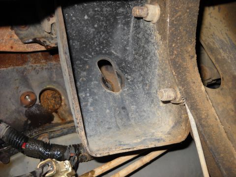 1993 Ford C-150 (Centurion Conversions) - Close-up view of a corroded metal bracket and bolts, likely from a vehicle's undercarriage.
