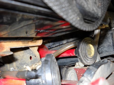 1993 Ford C-150 (Centurion Conversions) - A close-up view of various engine components, including hoses and red-painted metal parts, under a vehicle.