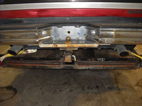 1993 Ford C-150 (Centurion Conversions) - Rear view of a truck's bumper and trailer hitch assembly, showing dual exhaust pipes.