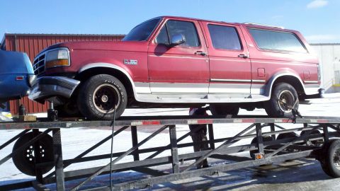 1993 Ford C-150 (Centurion Conversions) - A red SUV is parked on a trailer, possibly for transport or repair.