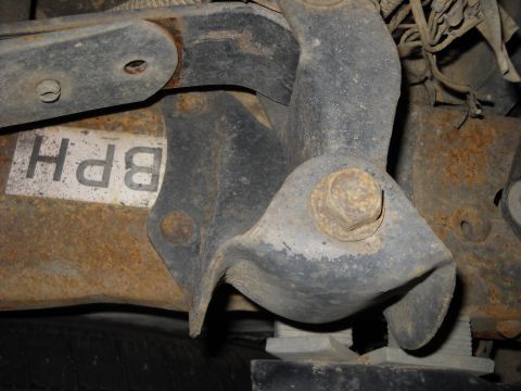 1993 Ford C-150 (Centurion Conversions) - Close-up of a rusty vehicle suspension part with a label that reads 'BPH'.