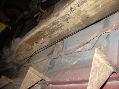 1993 Ford C-150 (Centurion Conversions) - The undercarriage of a vehicle is visible, with significant rust and wear on the frame.