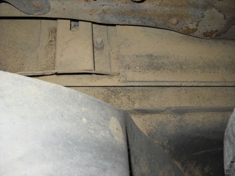 1993 Ford C-150 (Centurion Conversions) - The underside of a vehicle reveals its frame and suspension components covered in dust.