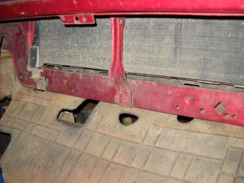 1993 Ford C-150 (Centurion Conversions) - The front of a red vehicle shows the radiator and surrounding support structure.
