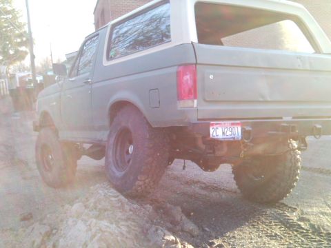 1989 Ford Bronco - This lifted 1989 Ford Bronco is shown from the rear, equipped with off-road tires and a tan removable top.