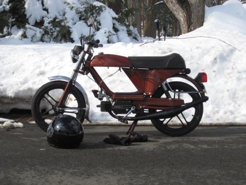 1981 Garelli Rally Sport - A brown moped sits on a stand in the snow, with a black helmet nearby.
