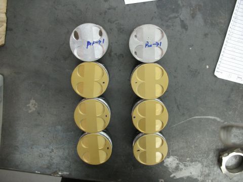 1995 Ford Probe - Eight pistons, two silver and six gold, are laid out on a workbench, some marked with blue ink.