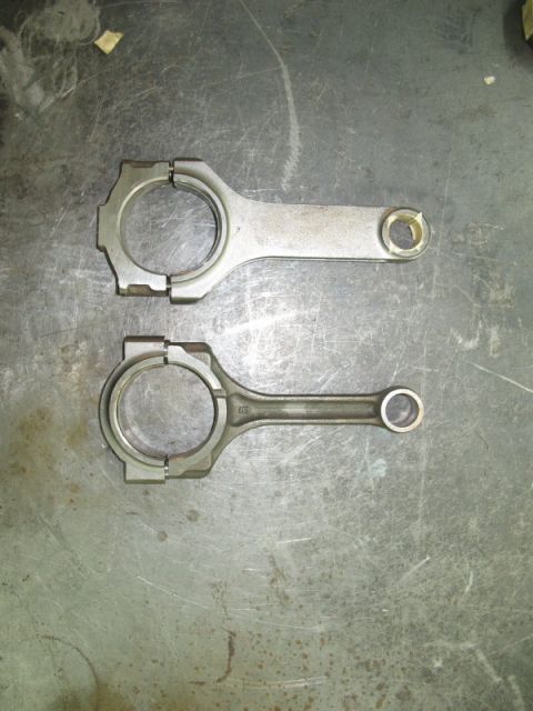 1995 Ford Probe - Two engine connecting rods are shown side-by-side on a workbench.
