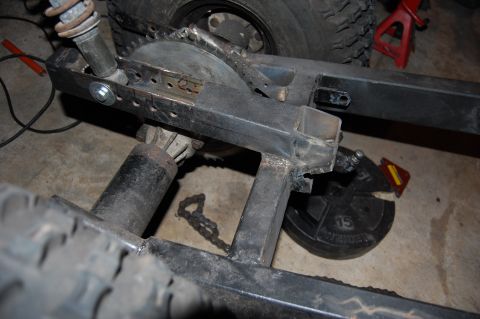 2010 Kawasaki BAYOU 220 - Close-up view of the rear swingarm, chain, and shock absorber assembly.