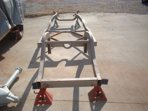 1969 Ford Torino - Car frame disassembled and supported on jack stands, with drivetrain components on the ground.