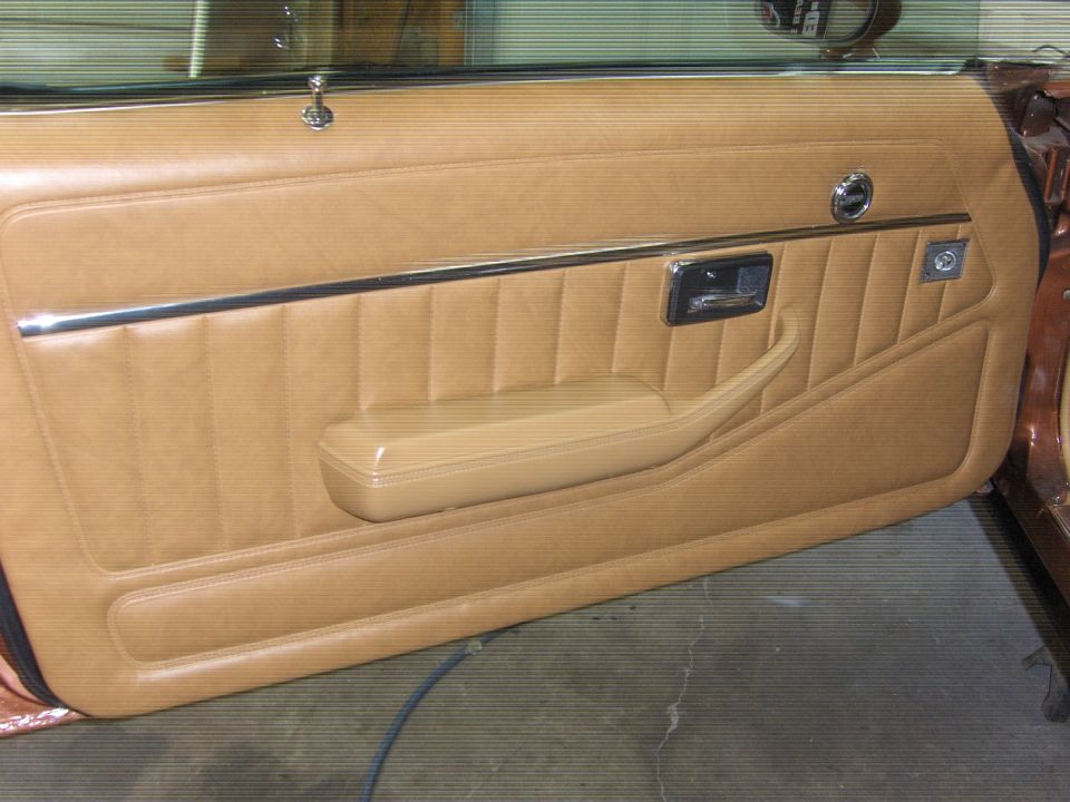 tan interior door panel with chrome trim and armrest