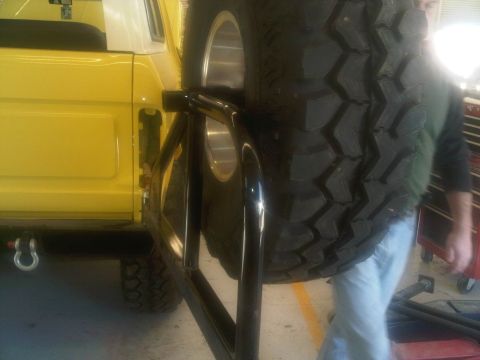 1978 Ford Bronco - Rear view of a yellow 1978 Ford Bronco, a spare tire carrier and a visible tow hook.