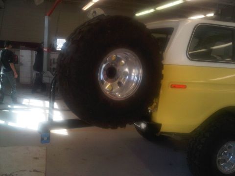 1978 Ford Bronco - Rear view of a 1978 Ford Bronco showing the spare tire mount and yellow/white paint scheme.