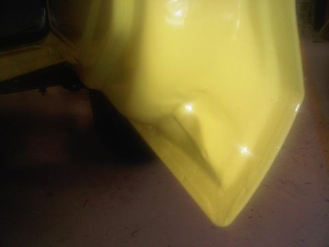 1978 Ford Bronco - A close-up shot focuses on the corner of a yellow vehicle's front fender and bumper area.