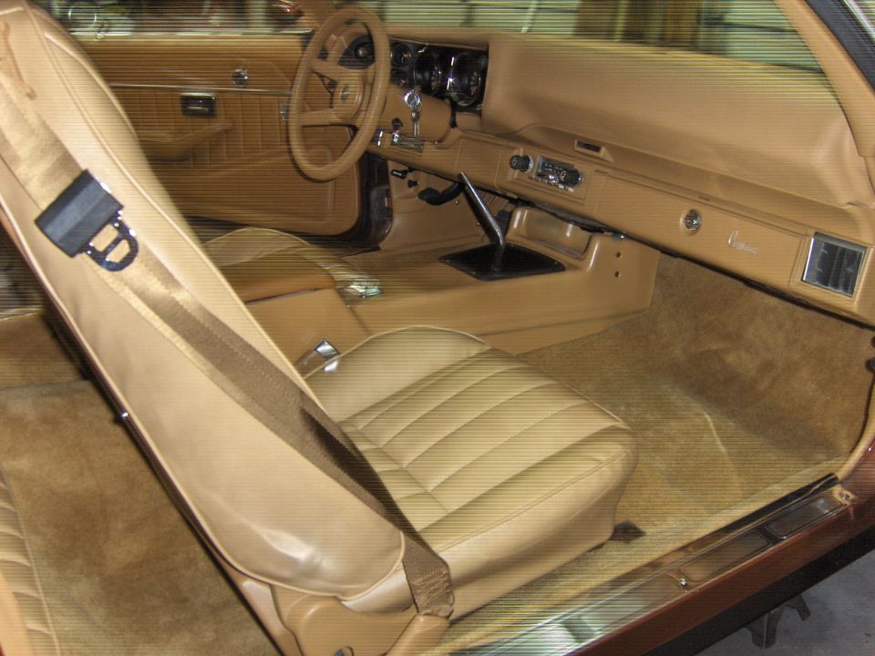 Tan interior of a 1979 Chevrolet Camaro, showing the driver's seat, dashboard, and center console