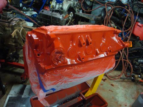 1989 Ford Bronco - Engine block painted orange and covered in plastic sheeting, with other engine parts in the background.
