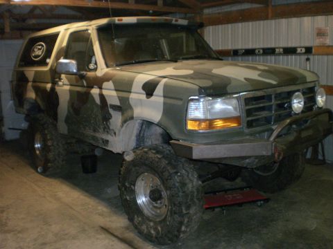 1995 Ford Bronco - This modified Ford Bronco is parked inside a garage, showing off its custom paint and off-road tires.