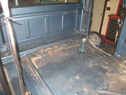 1976 Ford F-250 - The interior of a 1976 Ford F-250 truck cab is shown, revealing the floor and rear wall, with a shop vac and tool chest visible.