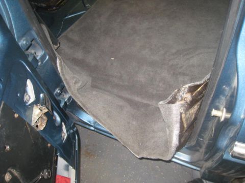 1976 Ford F-250 - The interior door jamb of a blue vehicle shows exposed insulation and carpet material.