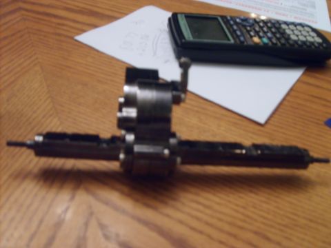 1989 Ford Bronco - A mechanical part, possibly from a vehicle's drivetrain, rests on a table with a calculator and papers nearby.