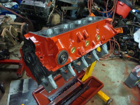 1989 Ford Bronco - Engine block on a stand, ready for rebuild. Background shows other automotive parts and engines.