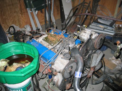 1984 Ford Bronco - Engine with blue valve covers and an oil drain pan sits on a stand.