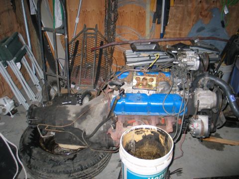 1984 Ford Bronco - An engine and transmission assembly is shown in a garage, resting on a tire with a bucket nearby.