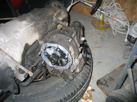 1984 Ford Bronco - Close-up of a vehicle's transmission and transfer case components, resting on a tire.