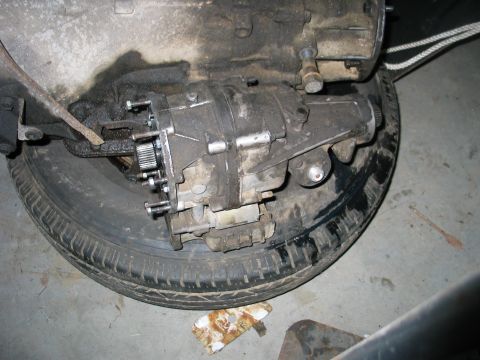 1984 Ford Bronco - Close-up view of a vehicle's transfer case assembly, which is positioned on top of a spare tire.