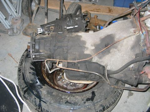1984 Ford Bronco - This image shows a vehicle's transmission and a tire, likely in a workshop or storage area.