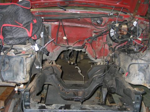 1984 Ford Bronco - The engine bay of a vehicle is shown with extensive wiring and exposed frame components.