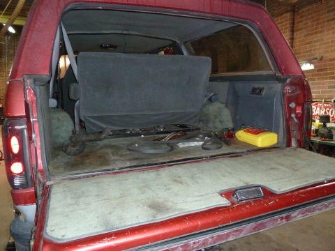 1993 Ford C-150 (Centurion Conversions) - Rear cargo area of a red SUV, with items stored inside and seats folded.