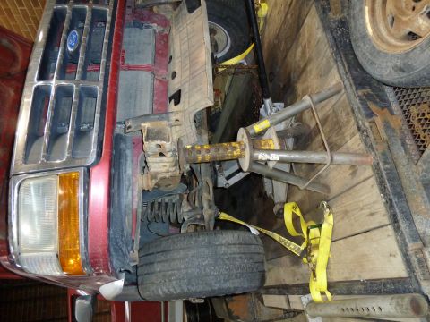 1993 Ford C-150 (Centurion Conversions) - Front view of a red Ford truck, possibly a 1993 model, secured on a trailer with yellow straps.