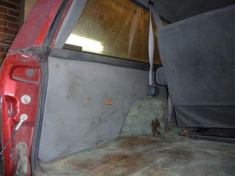 1993 Ford C-150 (Centurion Conversions) - The interior of a red vehicle with worn upholstery and carpeting is shown from the rear passenger side.