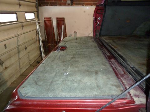 1993 Ford C-150 (Centurion Conversions) - The carpeted bed cover of a red pickup truck is shown from the interior perspective.