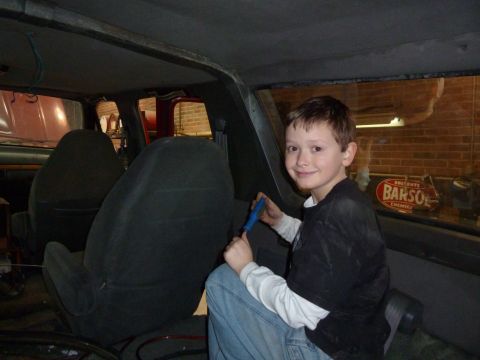 1993 Ford C-150 (Centurion Conversions) - Boy working on the interior of a vehicle, with a visible 'BARSOL' sign in the background.