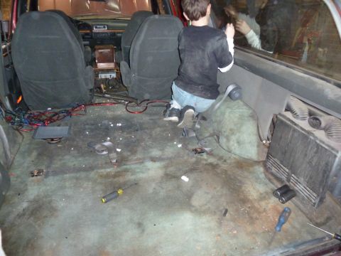 1993 Ford C-150 (Centurion Conversions) - The interior of a vehicle shows a messy floor with tools and wiring, and a child looking out the window.