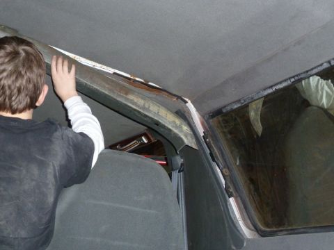 1993 Ford C-150 (Centurion Conversions) - A child's hand reaches for the interior roof trim of a vehicle, revealing signs of age and rust.