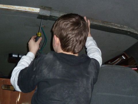 1993 Ford C-150 (Centurion Conversions) - A child is seen from behind, working on the interior of a vehicle with a screwdriver.