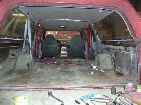 1993 Ford C-150 (Centurion Conversions) - The interior of a red van shows exposed wiring and two front seats, with the rear cargo area empty.