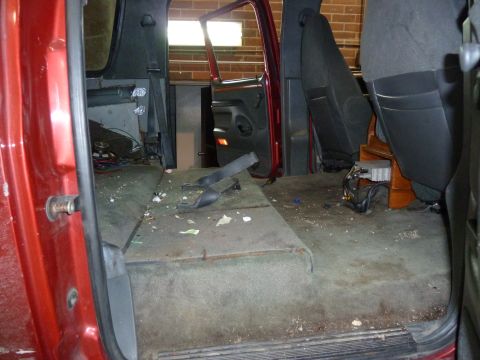1993 Ford C-150 (Centurion Conversions) - The interior of a red van shows a removed seating area and exposed wiring on the floor.