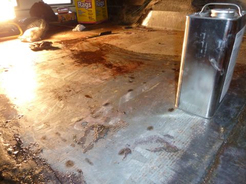 1993 Ford C-150 (Centurion Conversions) - The interior floor of a vehicle appears stained and dirty, with a metal container and a box of rags visible.