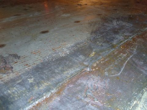 1993 Ford C-150 (Centurion Conversions) - The image shows a close-up of a weathered metal surface, likely a vehicle floor, with visible signs of wear and tear.